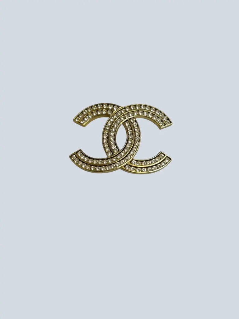 Gold-plated metal and rhinestone CC logo brooch.