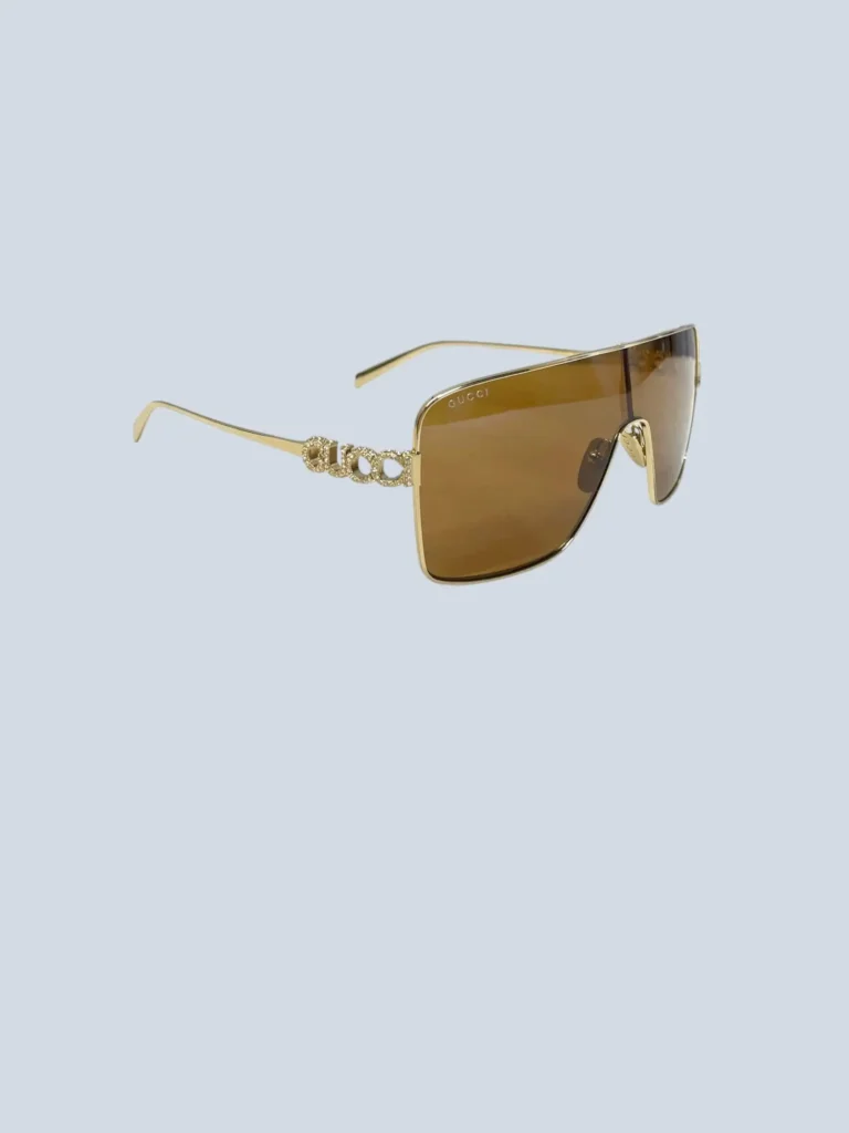 Oversized metal shield sunglasses with rhinestone logo.