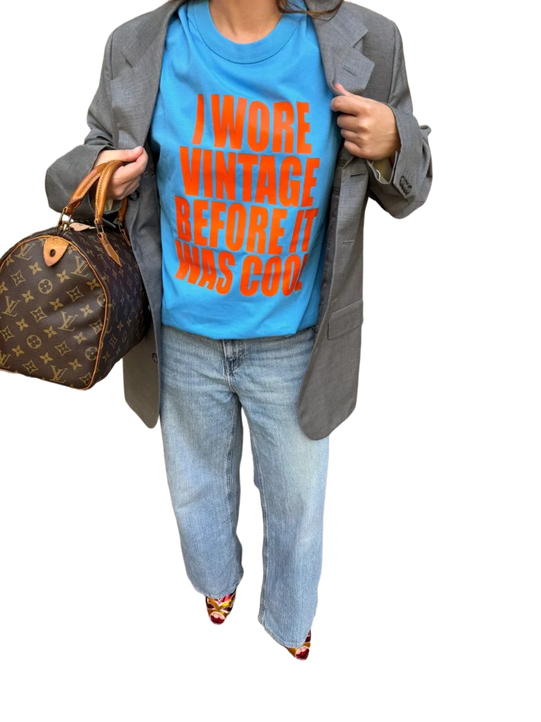 T-shirt blu con stampa arancione NOT OLD. JUST ICONIC. indossata con blazer grigio.